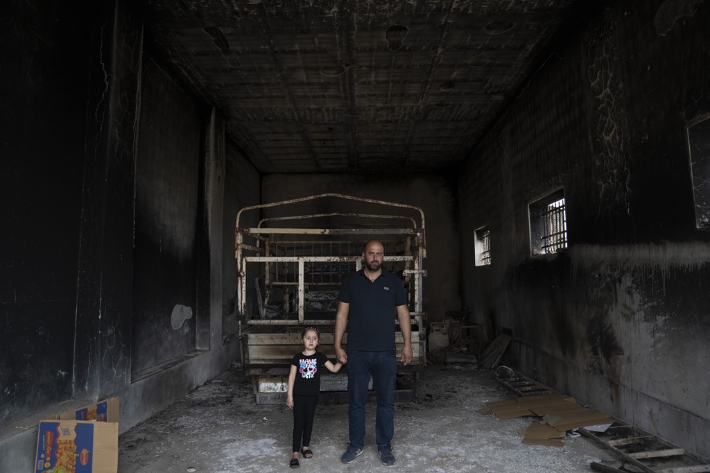 Ibrahim Dawabsha and his daughter, Ghena, with their burnt-out truck after a settler attack