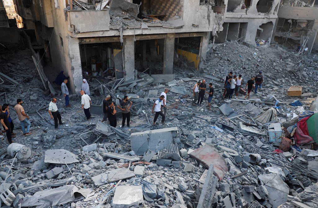 Palestinians inspect the site of an overnight Israeli strike on a house in Gaza City
