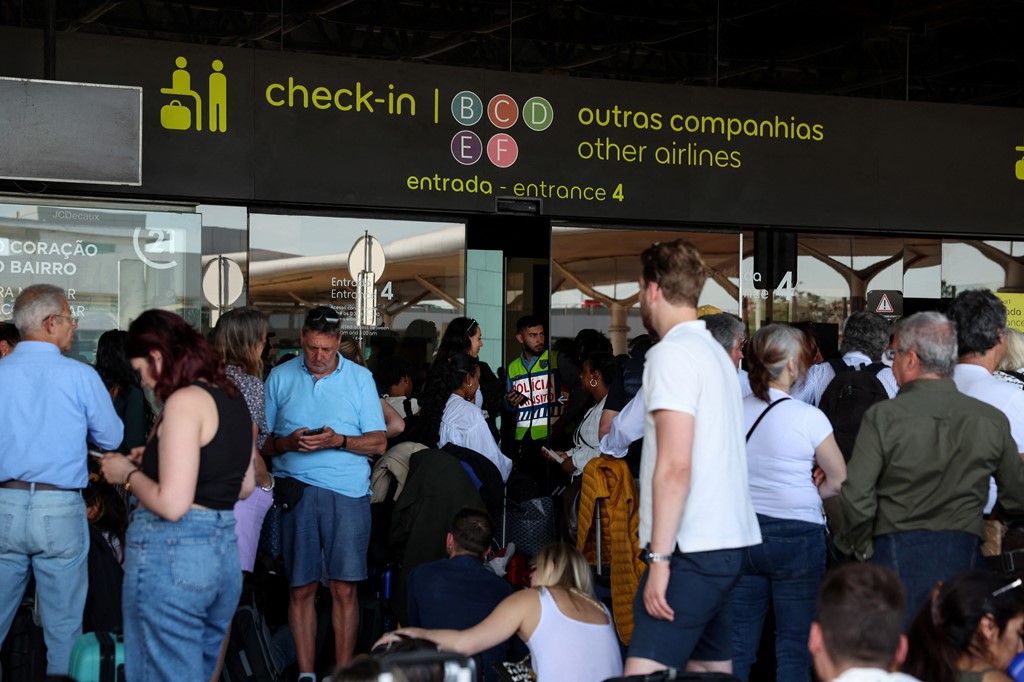 Des personnes attendent à l’extérieur de l’aéroport de Lisbonne pendant la panne