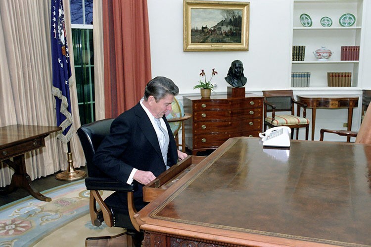 Ronald Reagan sits at the Oval Office desk following his inaugural parade in Washington in 1981