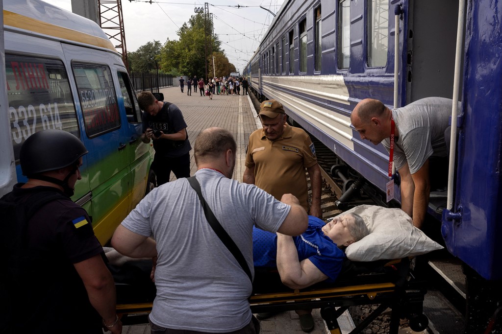 Volunteers of the East SOS organisation lift a woman on to an evacuation train
